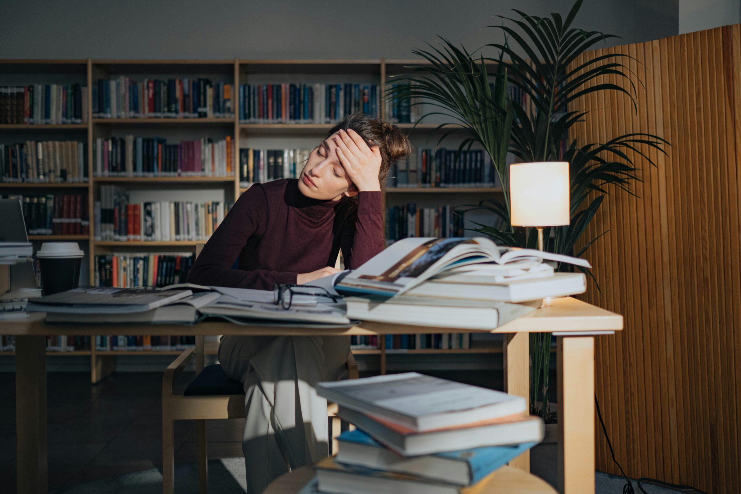 Personne découragée assise à un bureau avec pleins de cahiers.